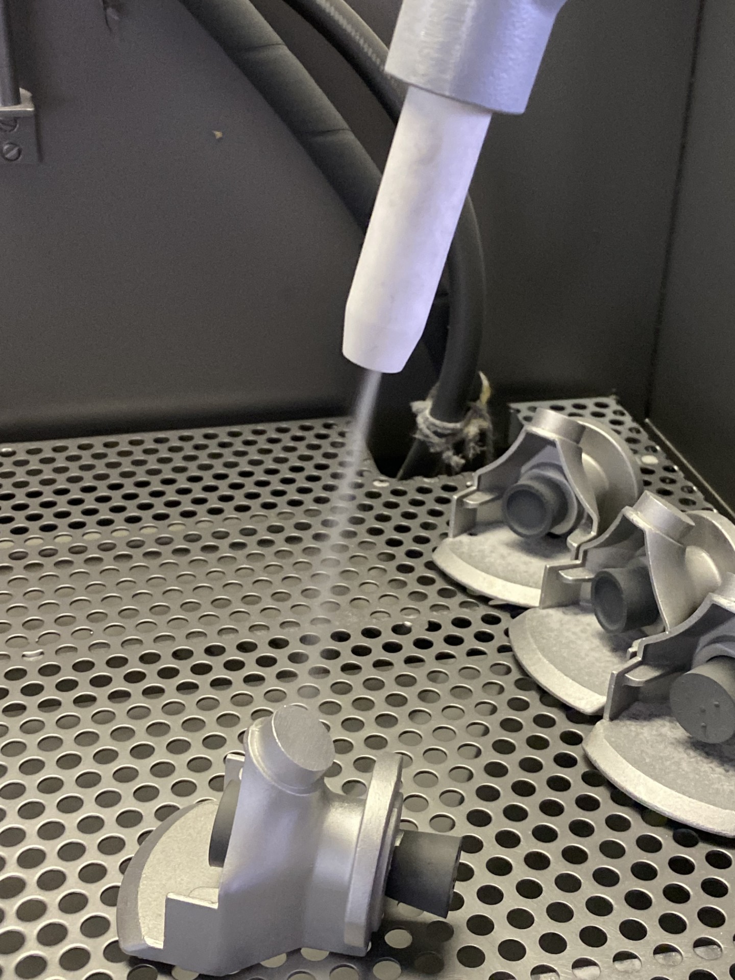 Glasperlenstrahlen von Metallbauteilen in einer Strahlkabine